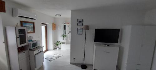 uma sala de estar branca com uma televisão numa parede branca em Maison De Marie em Donnaz