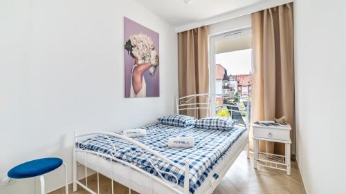 a small bedroom with a bed and a window at Baltic Garden Sztutowo Apartamenty PIAMOLA in Sztutowo