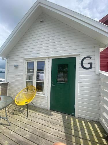 a house with a green door and a chair on a porch at Sjøberg Hotell og Ferie Leiligheter in Østhusvik