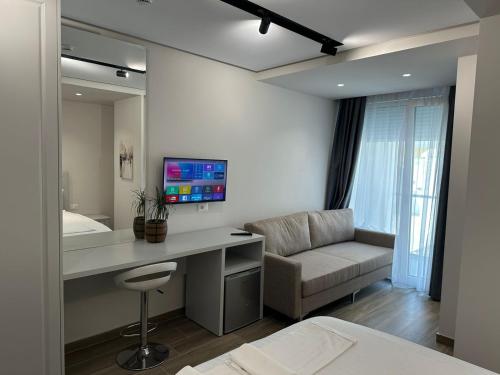 a bedroom with a desk and a couch and a television at Vila Kapllani Rooms in Durrës