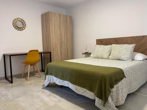 1 dormitorio con 1 cama y 1 silla amarilla en Suites Benalup Centro, en Benalup-Casas Viejas