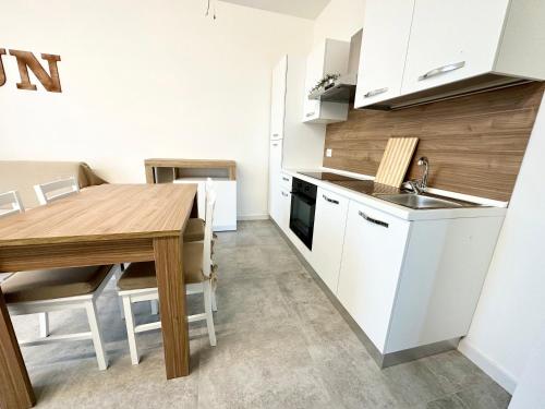 une cuisine avec des placards blancs et une table en bois dans l'établissement Lux apartments e, à Follonica