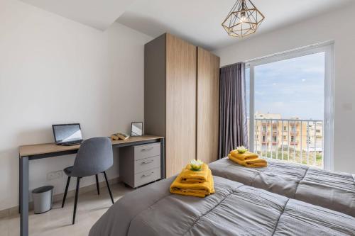 1 dormitorio con 2 camas, escritorio y ventana en Dome Sunset Views Apartment en Mellieħa