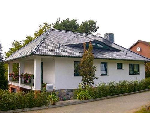 ein weißes Haus mit grauem Dach in der Unterkunft Ferienwohnung am Wurlsee in Lychen