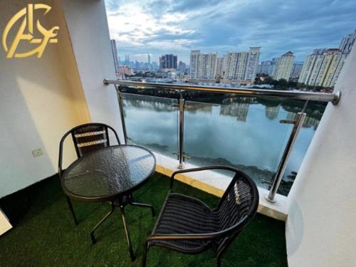 2 stoelen en een tafel op een balkon met water bij Honeymoon Suite By A Legacy Hotel - KLCC Lake View in Kuala Lumpur