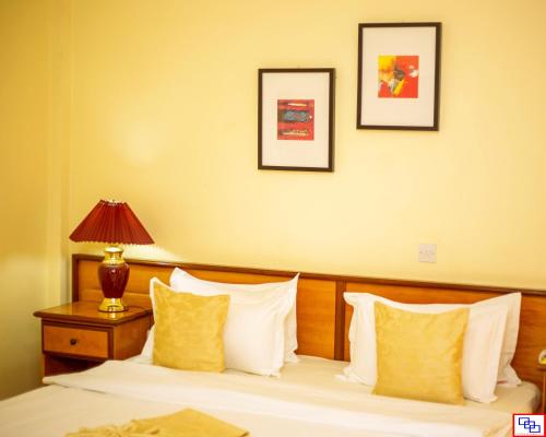 a hotel room with a bed with yellow and white pillows at Hotel Marjorie `Y` in Tema