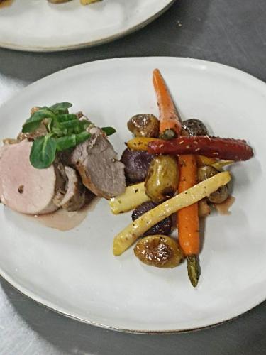 a white plate with meat and vegetables on a table at La Sapinière St Lary Soulan in Saint-Lary-Soulan