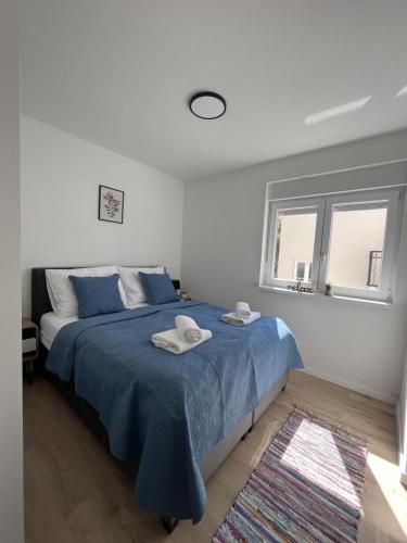 a bedroom with a blue bed with towels on it at Apartmani Ora in Komarna