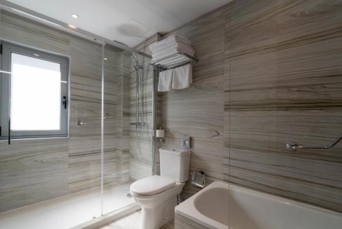 a bathroom with a toilet and a bath tub at Hotel Plaza in A Coruña
