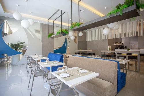 ein Restaurant mit weißen Tischen und blauen Stühlen in der Unterkunft Hotel Monte Puertatierra in Cádiz