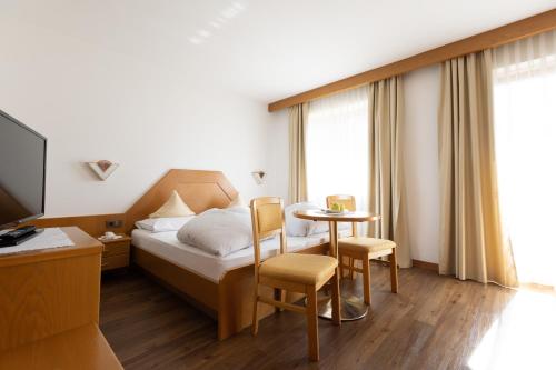 um quarto de hotel com uma cama, uma mesa e cadeiras em B&B Hotel Mair am Turm em Tirolo