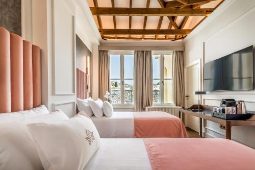 a hotel room with two beds and a television at Palacio Gran Vía, a Royal Hideaway Hotel in Granada