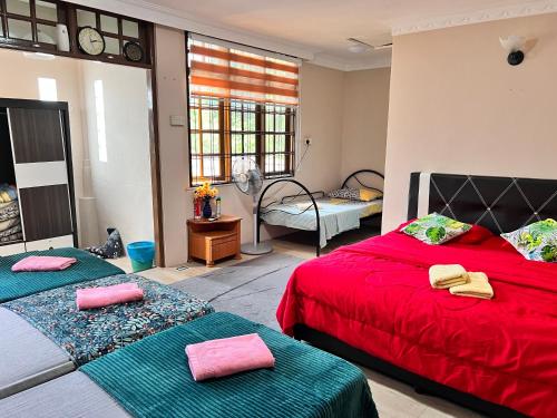 1 Schlafzimmer mit 2 Betten mit roter Bettwäsche und grünen Decken in der Unterkunft Iman Homestay: Sri Kandis in Kuching