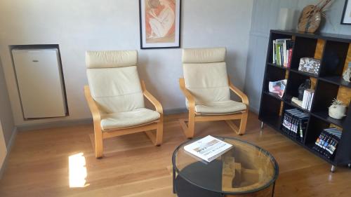 - deux chaises et une table en verre dans le salon dans l'établissement VELOFT, à Villebernier