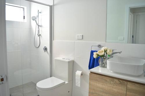 a white bathroom with a toilet and a sink at Elegant & Convenient New House at Leppington in Leppington
