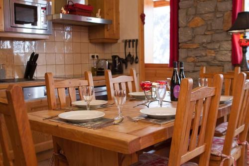 une table en bois avec des assiettes et des verres à vin dessus dans l'établissement Venus - 2 bedroom apartment next to the slopes, à Sainte-Foy-Tarentaise