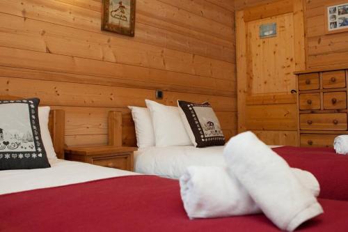 deux lits dans une chambre aux murs en bois dans l'établissement Venus - 2 bedroom apartment next to the slopes, à Sainte-Foy-Tarentaise