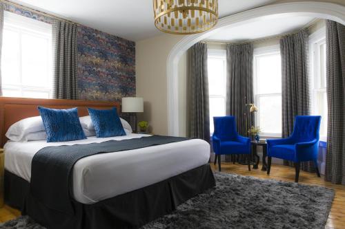 a bedroom with a bed with blue chairs and a chandelier at Gilded in Newport