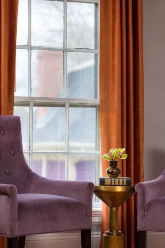 a window with two chairs and a table with a vase of flowers at Gilded in Newport