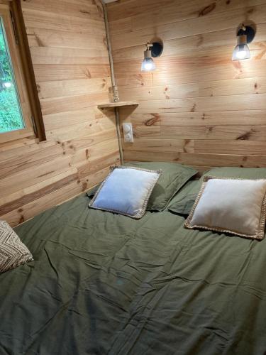 a bed in a log cabin with two pillows on it at La Roulotte des Bois 