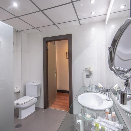 a bathroom with a sink and a toilet and a mirror at Hotel Monte Puertatierra in Cádiz