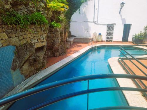 a blue swimming pool with a stone wall at Apartamento Playa Calzoa in Vigo