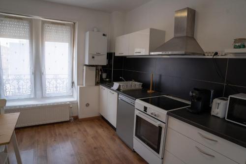 une cuisine avec des armoires blanches et un four à plaques de cuisson dans l'établissement Le Luma, à Colmar