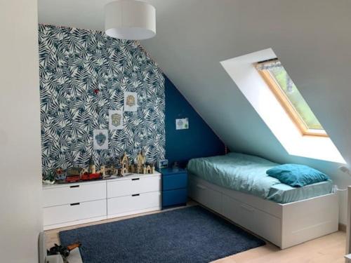 1 dormitorio con 1 cama con pared azul en Charmante Maison avec jardin proche Rennes, en Saint-Grégoire