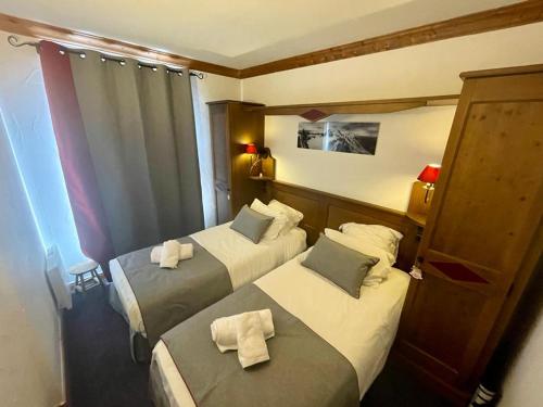 une chambre d'hôtel avec deux lits avec des serviettes dessus dans l'établissement Arc 1950 - Appt 2CH - 6 pers - Rés 5* luxe - Piscine, sauna, hamman, jacuzzi - Classé 5 cristaux Paradiski, à Arc 1950