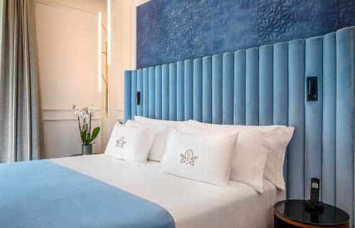 a bed with a blue headboard and white pillows at Palacio Gran Vía, a Royal Hideaway Hotel in Granada