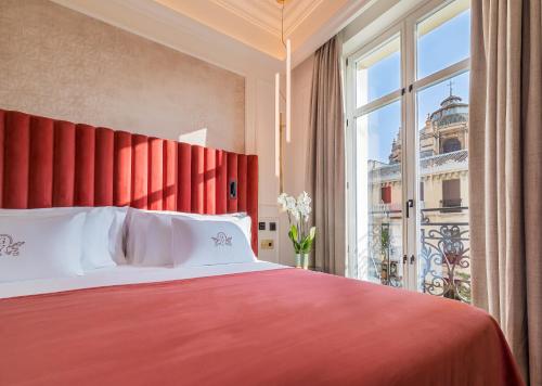 a bedroom with a red bed and a large window at Palacio Gran Vía, a Royal Hideaway Hotel in Granada