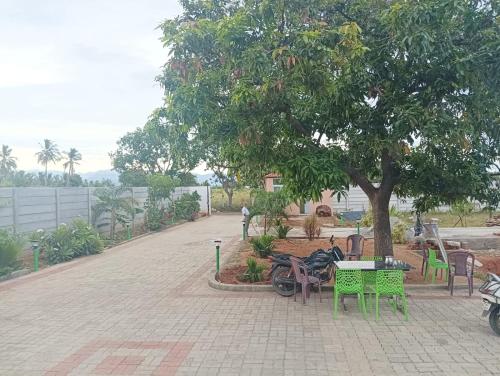 un parque con mesas, sillas y un árbol en ANTARA STAY, en Coimbatore