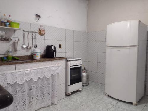 Il comprend une cuisine équipée d'un réfrigérateur blanc et d'une cuisinière. dans l'établissement Casa para temporada em Rio das Ostras, à Rio das Ostras