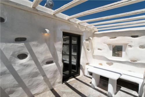 een wit gebouw met een bank op een patio bij Villa Aspro Paros 1 in Drios