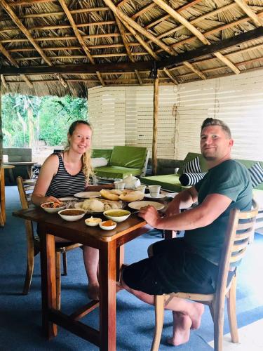 a man and a woman sitting at a table with food at Sitha's Heaven in Ella