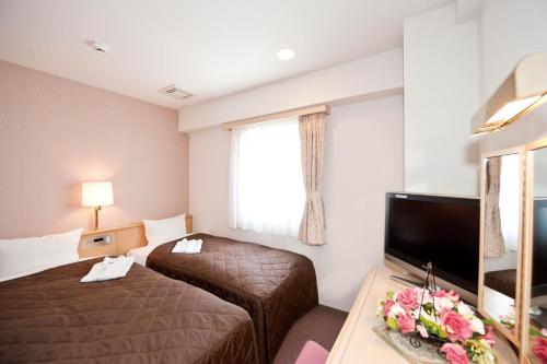 a hotel room with two beds and a flat screen tv at Hotel Unisite Sendai in Sendai