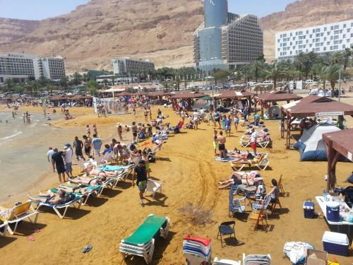 um grupo de pessoas numa praia com edifícios em Rose Dead Sea Neve Zohar em Neve Zohar
