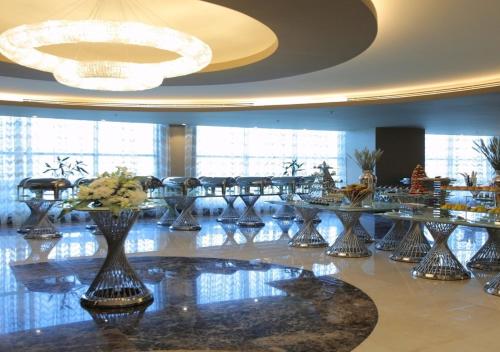 a dining room with tables and a chandelier at Kuwait Grand Hotel in Kuwait