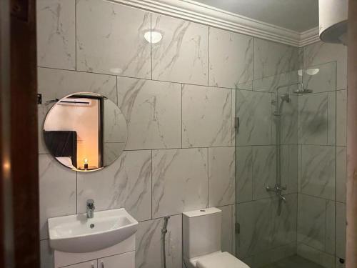 a bathroom with a shower and a sink and a mirror at After 5 Apartment 2 3 spacious en-suite bedrooms in Freetown