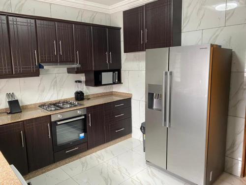 a kitchen with wooden cabinets and a stainless steel refrigerator at After 5 Apartment 1- 3 spacious en-suite bedrooms in Freetown