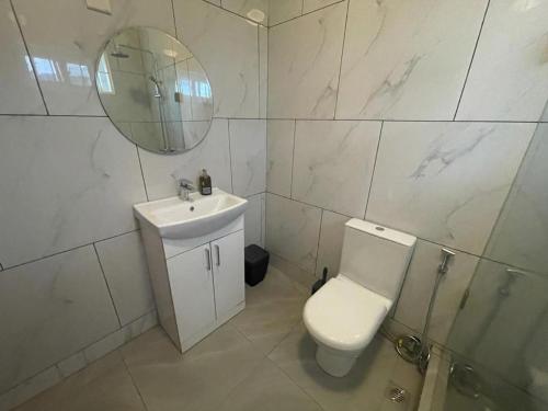 a bathroom with a toilet and a sink and a mirror at After 5 Apartment 1- 3 spacious en-suite bedrooms in Freetown