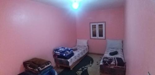 Ahermoumou的住宿－Dar El mokhtar Ighazran，一间设有两张床和两张搁脚凳的房间