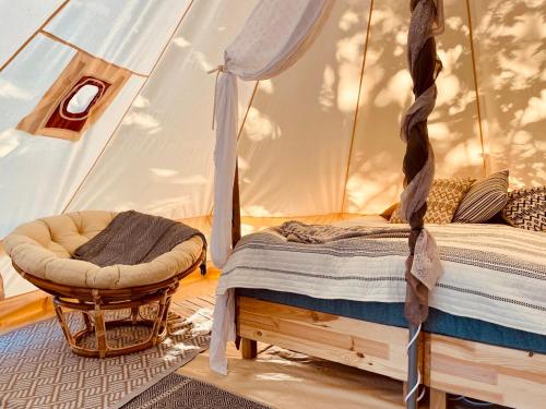 a bedroom in a tent with a bed and a chair at koh tenta a b&b in a luxury glamping style in Mariefred