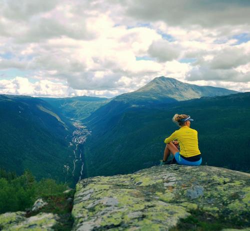 a person sitting on the edge of a rock overlooking a valley at Gausta Lodge med elbillader, nærhet til Gaustatoppen Ski in ski out in Gaustablikk