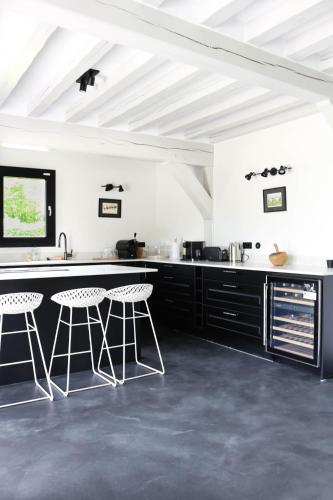 une cuisine avec comptoirs et tabourets en noir et blanc dans l'établissement Villa Fleurie, à Grandchain