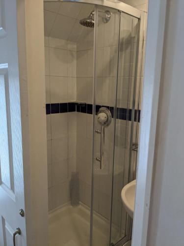 a shower with a glass door next to a sink at The Tudor Hotel in Harrow