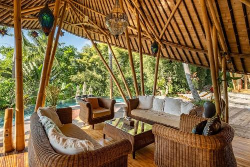 ein Wohnzimmer mit Sofas und Stühlen in einem Pavillon in der Unterkunft Harmony House, Bamboo House with Pool view in Bringkit