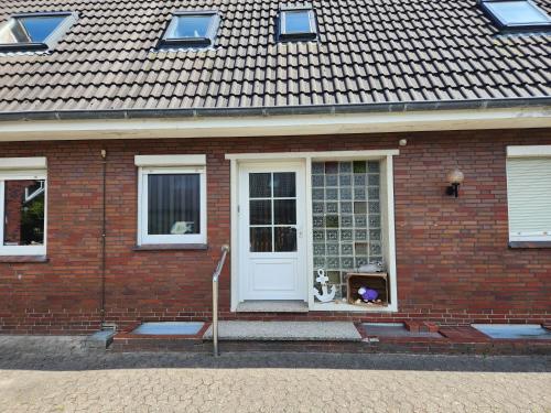 une maison en briques avec un chien assis dans la porte d'entrée dans l'établissement Gästehaus Norddeich, à Norden