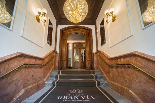 a hallway with stairs and a chandelier at Palacio Gran Vía, a Royal Hideaway Hotel in Granada