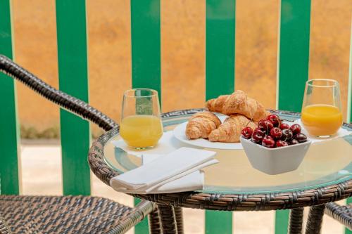 a table with a plate of food and two glasses of orange juice at Hotel Dei Pini in Alghero